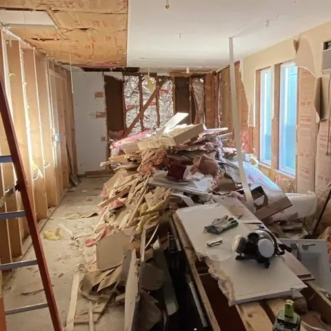 Room piled with torn-out drywall, insulation, and debris before the cleanout
