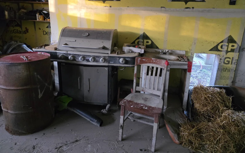 Garage with an old gas grill, steel drum, and chair before removal