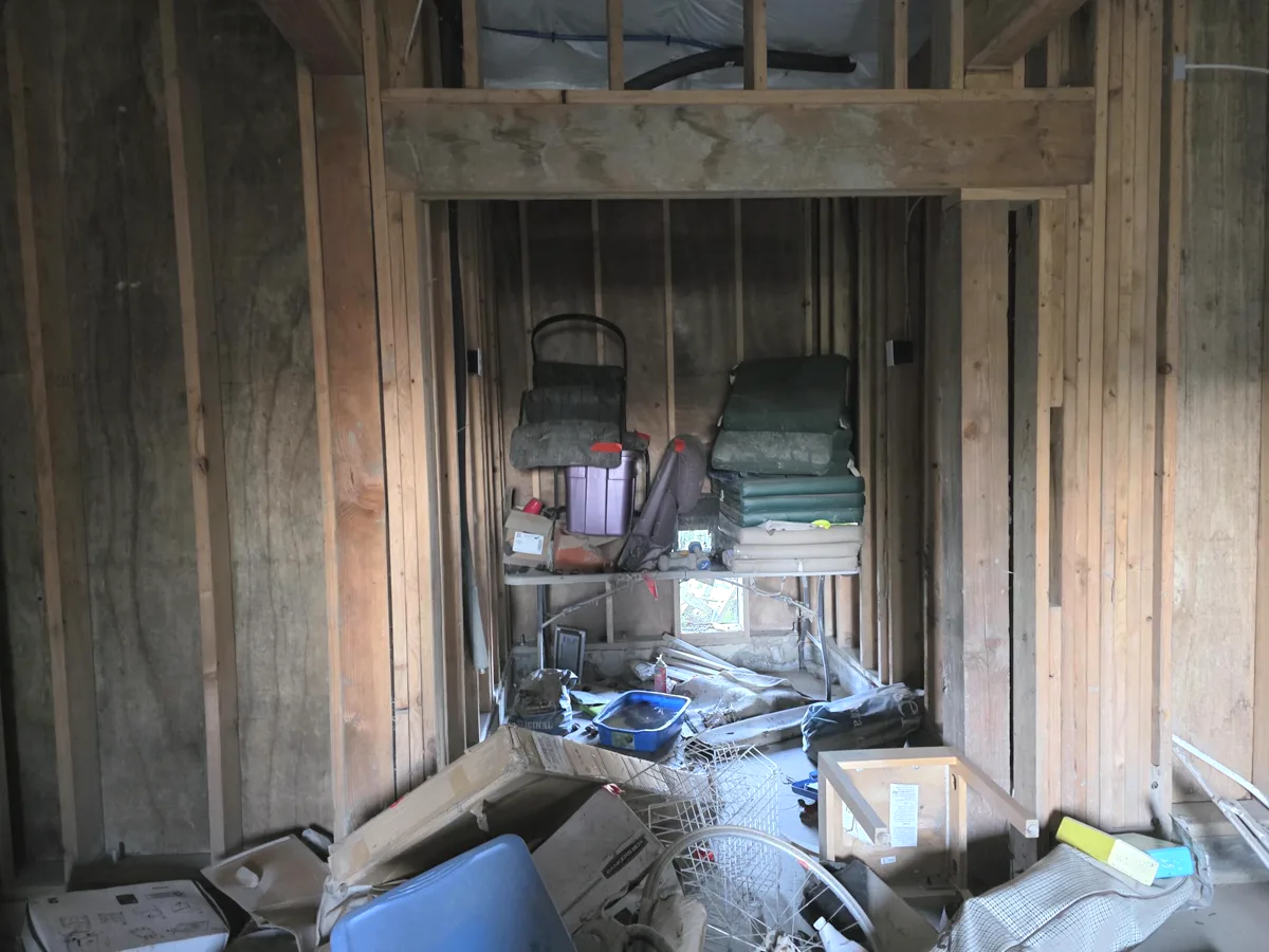 Storage area filled with boxes, cushions, and loose household items