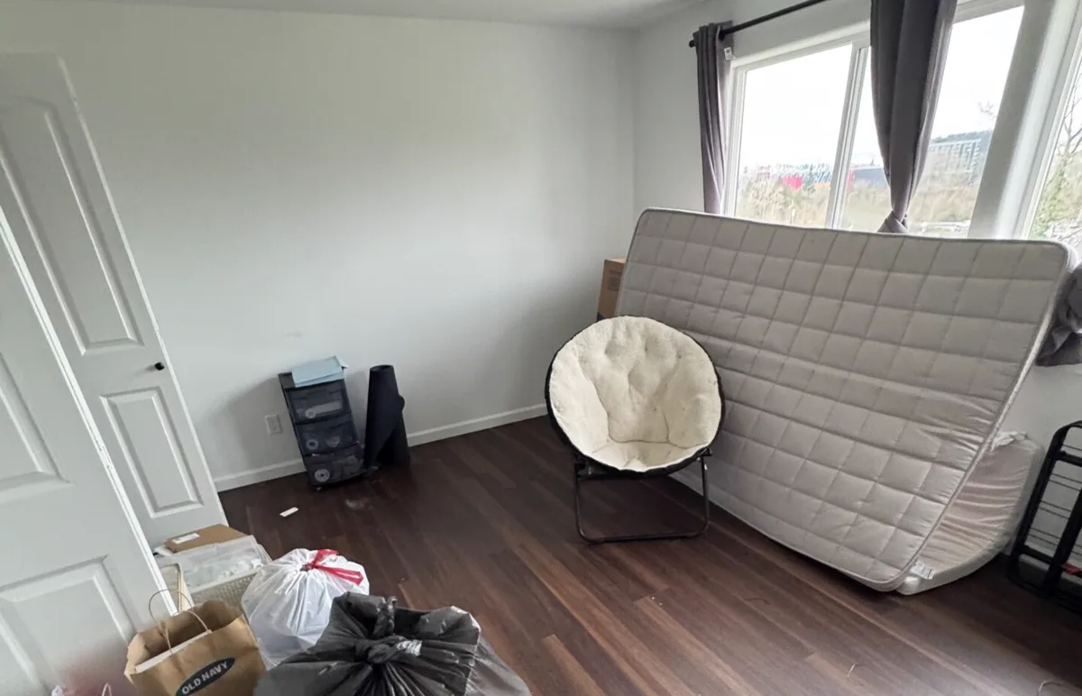 Mattress leaning against a bedroom wall beside bagged items for pickup