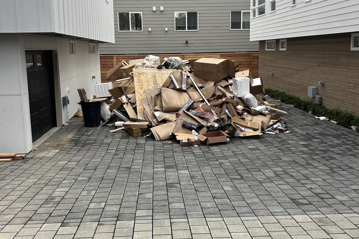 Large pile of cardboard boxes and packaging in a townhouse courtyard