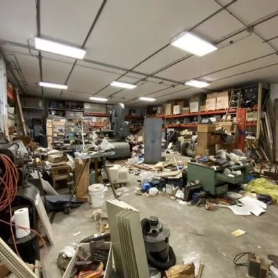 Warehouse before the cleanout, with equipment and debris across the floor